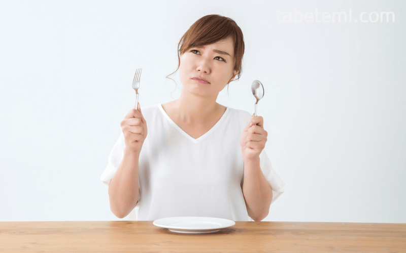 スプーンとフォークを両手に持つ女性